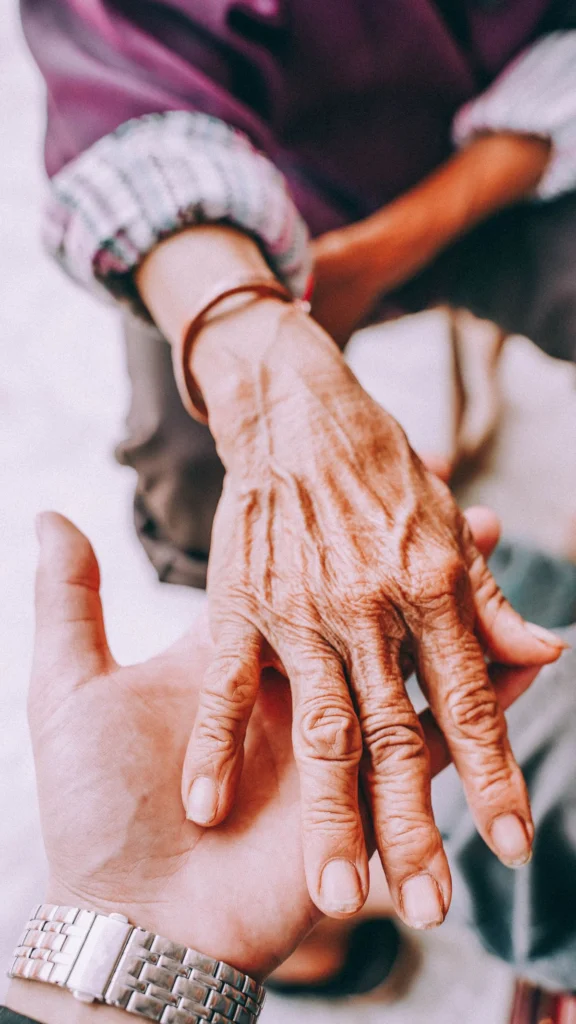 A younger hand resting gently on an older person's hand