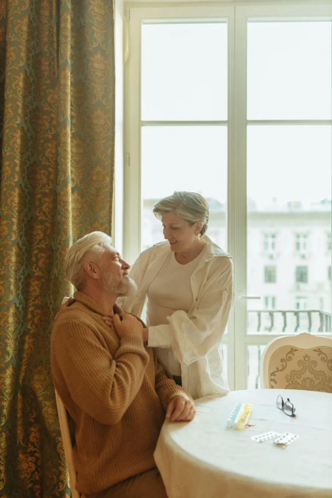 An older couple at home together beside a sunlit window